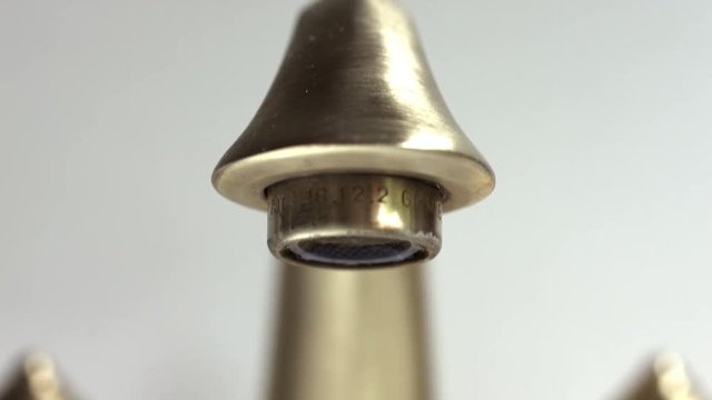 Panning down Dramatic Footage of Leaking Bathroom Faucet Over Gray Background.