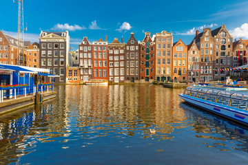 Beautiful typical Dutch dancing houses at the Amsterdam canal Damrak in the sunny evening, Holland, Netherlands.