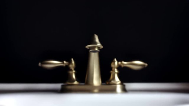Dramatic Footage of Leaking Bathroom Faucet Getting in Focus Over Black Background.
