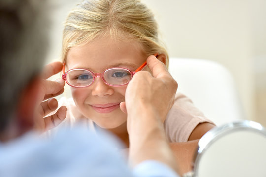 Little Girl At The Optician Trying Different Eyeglasses