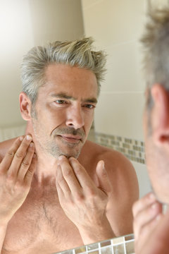 Mature man in bathroom checking beard