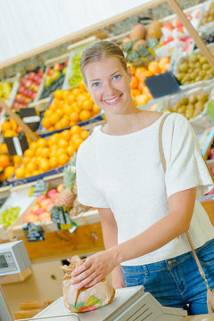 Lady weighing produce in paper bag