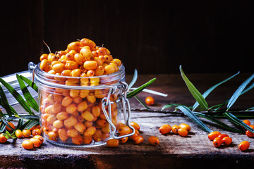 Fresh sea buckthorn in a glass jar. Vintage wooden background, l
