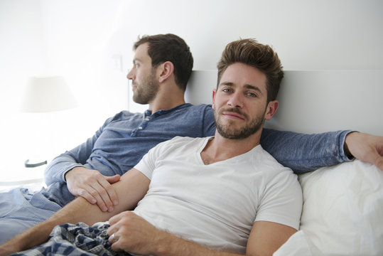 Portrait Of Gay Male Couple At Home Relaxing In Bed Together