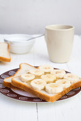 Close-up of breakfast with two sandwiches with honey and banana and cup of black coffee on table