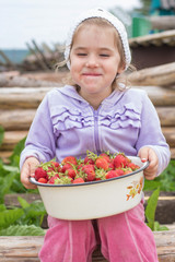 Маленькая, красивая, замечательная девочка кушает клубнику. Хорошенькая девочка смеётся. The little, beautiful, remarkable girl eats strawberry. The pretty girl laughs.