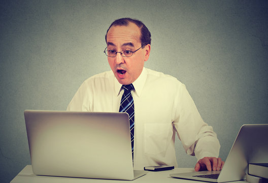 shocked man sitting in front of laptop computer