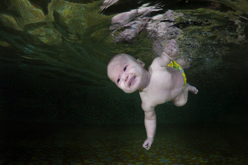 4 months infant learning to swim underwater in waterbaby class in the pool