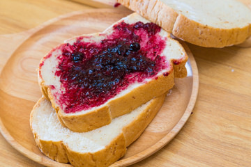 Bread with blackcurrant jam on wooden table