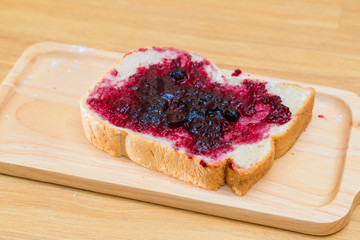 Bread with blackcurrant jam on wooden table