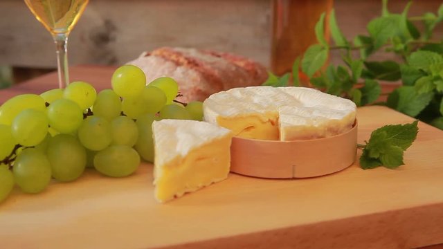 Camembert with white wine, grapes and bread. circular movement of the camera