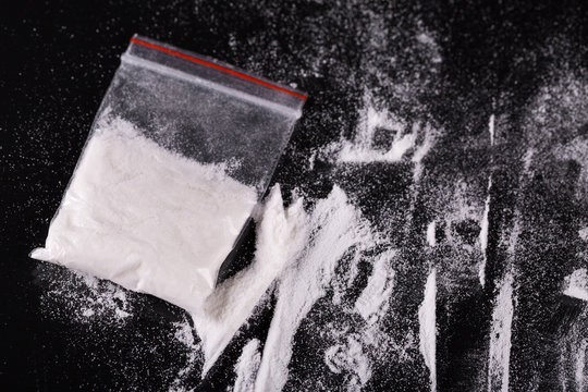 Cocaine in plastic packet on black background, closeup 