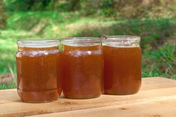 Fresh honey in glass jars on wooden table.