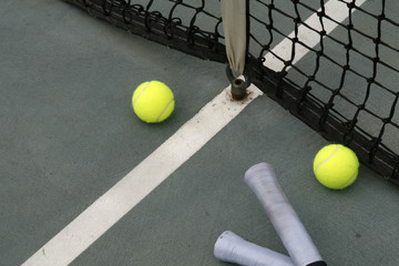 tennis ball, racket grip and net on hard court