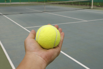 tennis ball and hand on hard court