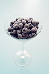 Frozen blueberries in martini glass isolated on calm and pastel background. Still life image of frozen berries arranged in artistic manner. - 120272581