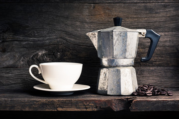 still life photography : old espresso maker with coffee beans and white coffee cup on old wooden shelf