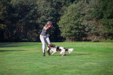 a woman and her dog p;aying in the meadow