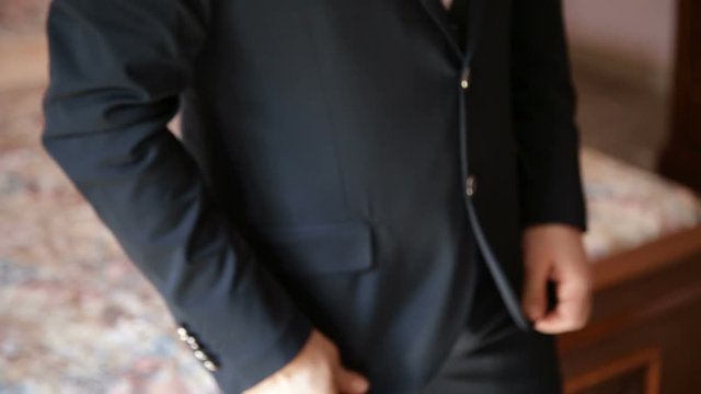 Giovane uomo Sposo si sta abbottonando la sua lussuosa giacca nera davanti a uno specchio