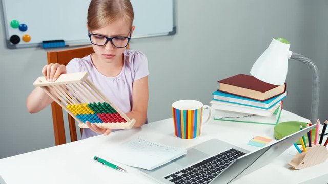 Portrait student girl 7-8 years using abacus in her desk at home