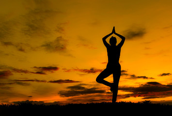 Fototapeta na wymiar Silhouette young woman practicing yoga on the beach at sunset.