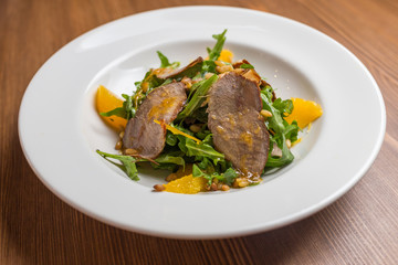 salad with baked duck on white plate