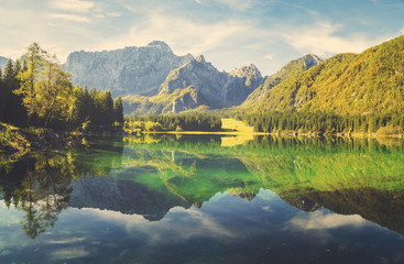 Fototapety  Alpejskie jezioro o świcie, pięknie oświetlone góry, retro kolory, vintage