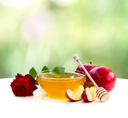 Honey, red apples and red rose on a white table on the blur natural background with space for text