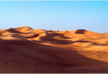 Fototapeta na wymiar desert dune background on blue sky. Arabian desert near the city of Dubai. Mountains and hills of colored sand