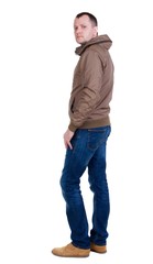 Fototapeta premium Back view of handsome man in brown windcheater looking up. Standing young guy in jeans. Rear view people collection. backside view of person. Isolated over white background.