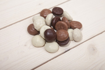 Pile of Dutch candy chocolate pepernoten on white wooden background
