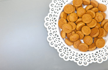 Traditional Dutch candy pepernoot on white plate on grey background
