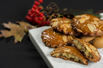 Typical Dutch filled spicy  cookies with almonds on autumn colored and dark background