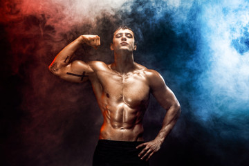 Naklejka na ściany i meble Portrait of muscular man posing at camera with shirtless body, misty smoky background