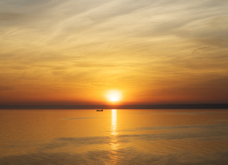 Bright sunset. Tranquil Sea. Fishing boat in the rays of the setting sun
