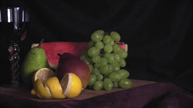 Still life with fruits on wood on black and violet fabric  background