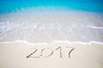 2017 handwritten on sandy beach with soft ocean wave on background
