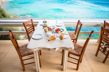 Traditional lunch with delicious fresh greek salad, frappe and brusketa served for lunch at outdoor restaurant with beautiful view on the sea and port