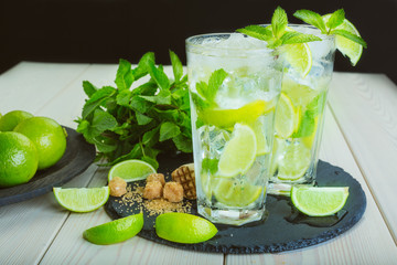 Two fresh mojitos cocktail on wooden background. Mojitos with mint leaves, lime and ice. 