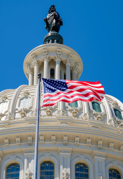 The american flag waving in front of the Capitol dome in Washing