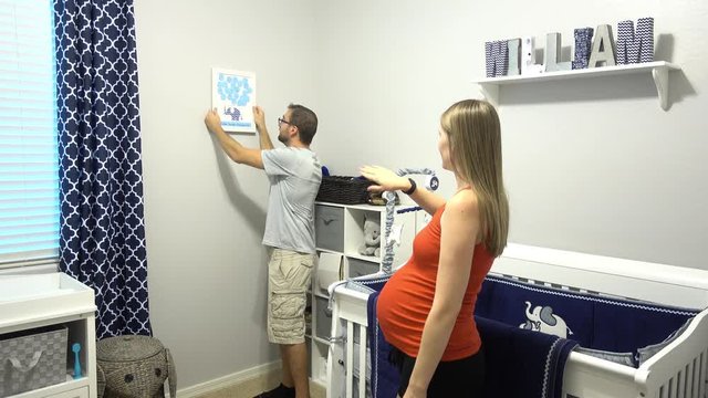 A young expecting couple clean and prepare their new nursery before the birth of their new baby.  	