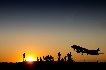 Fototapeta na wymiar Group of people watching commercial airplane taking off during sunset on a mountain