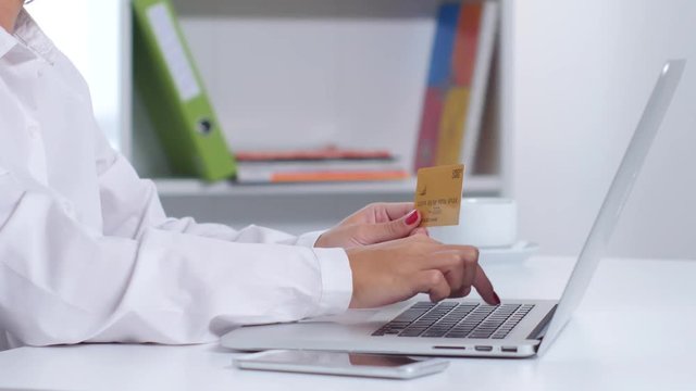 Girl makes online purchasing using white laptop in the office. Close up