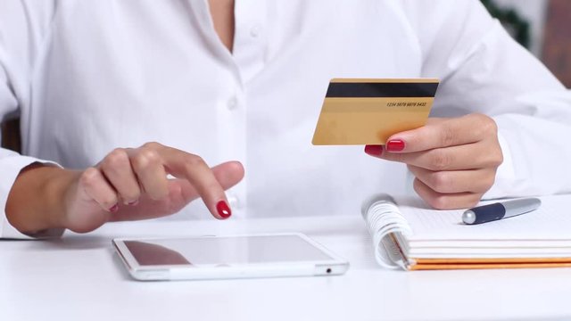 Girl completes an online purchase and enters the data on the card. Close up