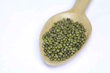 Green beans in a wooden spoon on a white background .