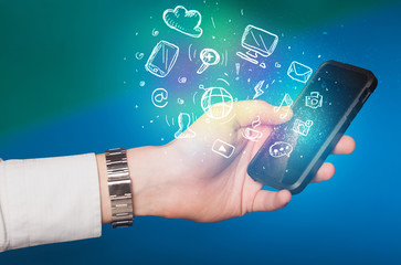 Hand holding smartphone with media icons