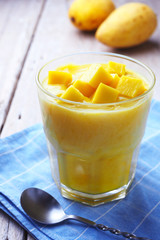 Naklejka na ściany i meble Close up of a healthy glass of mango yogurt smoothie on a wooden table.