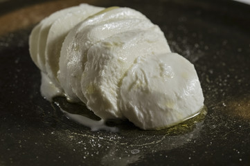 Dish of Italian mozzarella on dark plate with olive oil