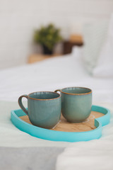 Two mugs on a tray white bed, breakfast concept