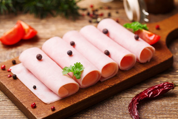 Delicious canned cooked ham on a wooden board with spices.